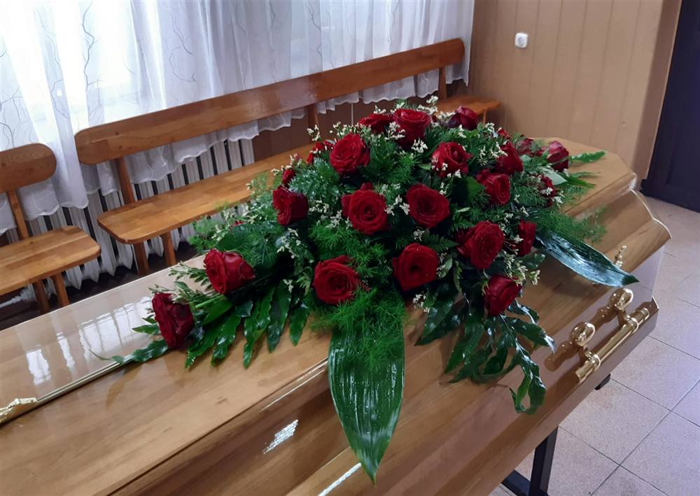 Stroik z czerwonych róż na jasnej trumnie